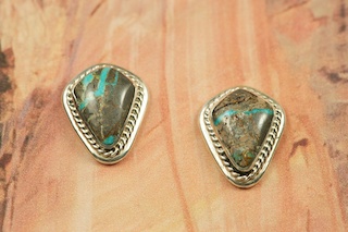 Genuine Sunnyside Turquoise set in Sterling Silver Post Earrings. The matrix on this rare stone is outstanding. The Sunnyside mine is located in northern Nevada near the town of Tuscarora in the Tuscarora mountain range. The mine is no longer in operation as it has become part of a gold mining operation and a privately owned ranch. The Sunnyside mine was mined mostly in the 70's. You won't find much of this great turquoise around anymore except for old stashes. Created by Navajo Artist Arkie Nelson. Signed by the artist.